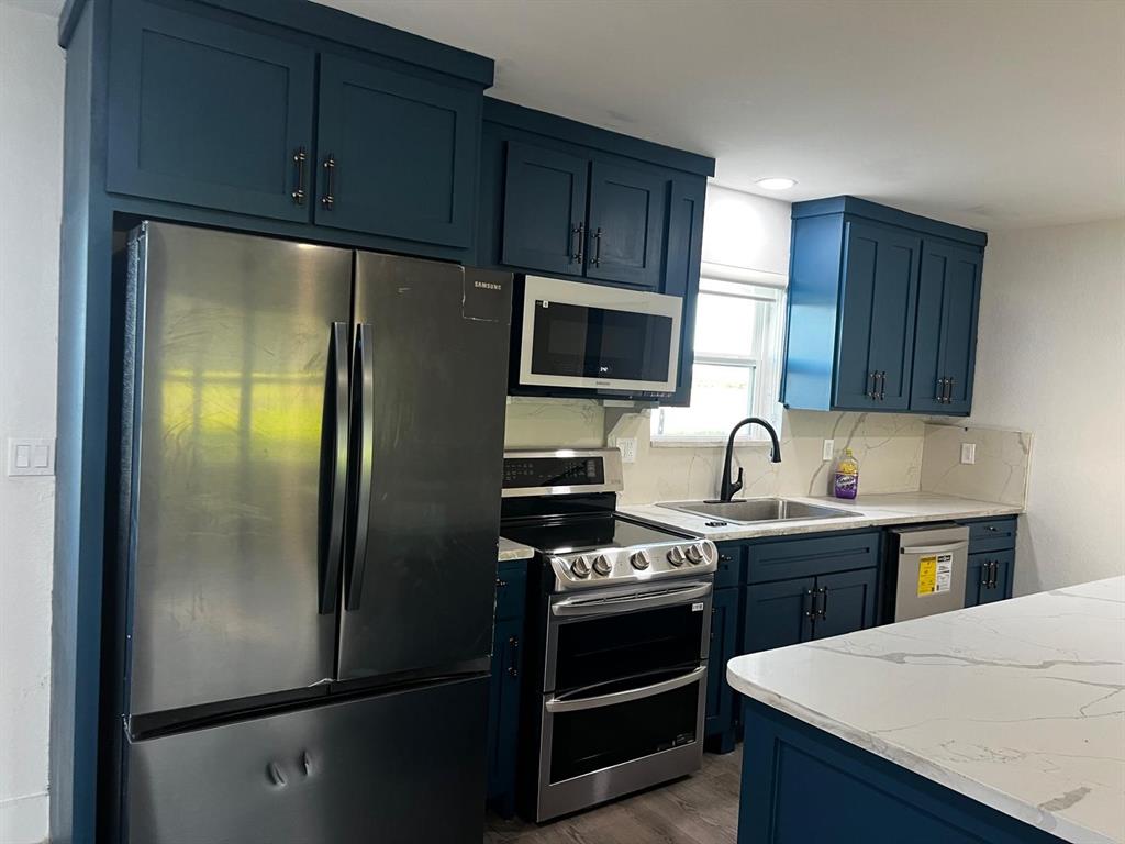 2025 County 1415 Road Bonham, TX 75418 - Photo 6 of 25 Kitchen featuring deep blue cabinetry, stainless steel appliances, a double oven range, and a white countertop with gray veining