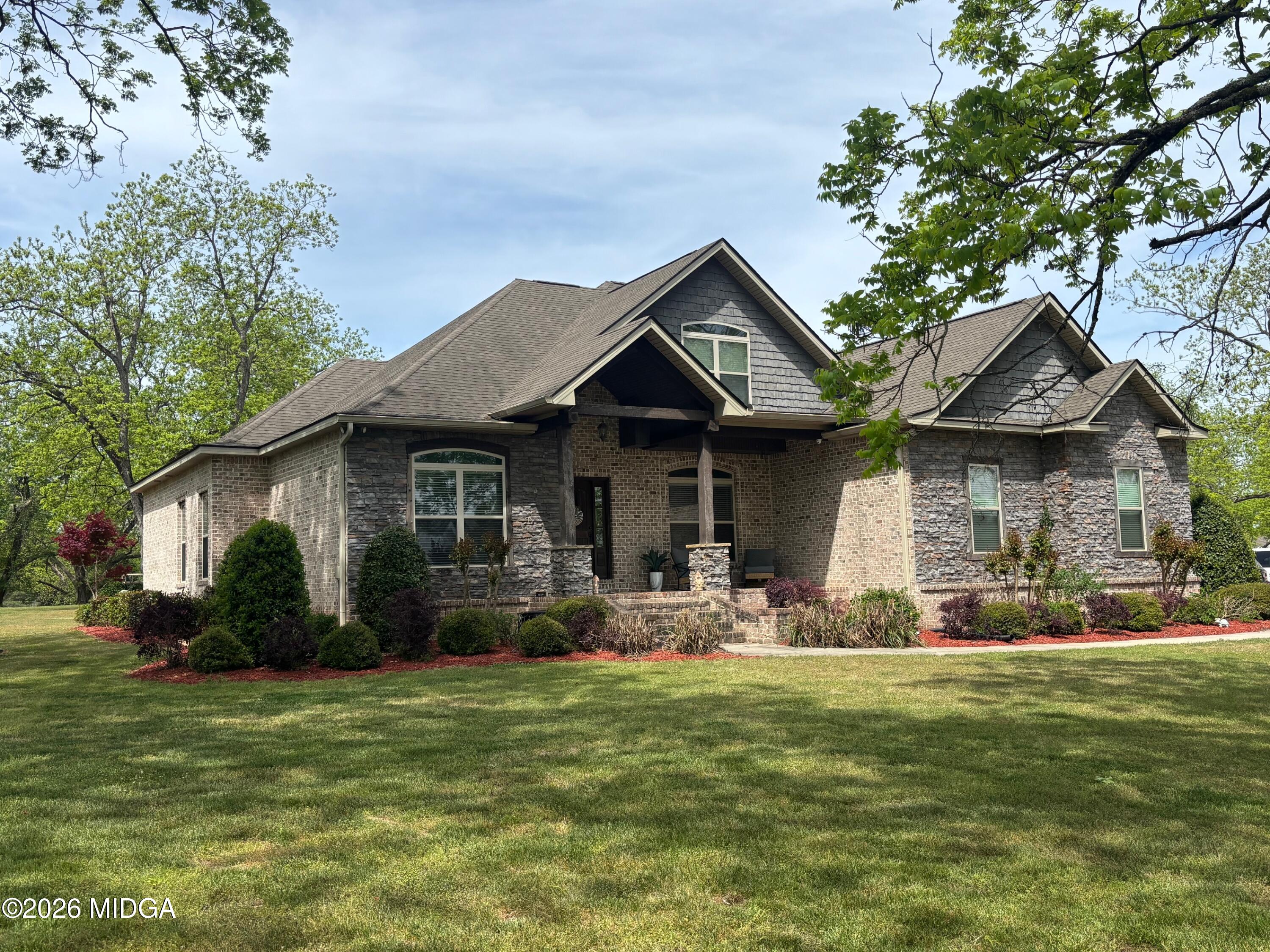 a front view of a house with a garden and trees