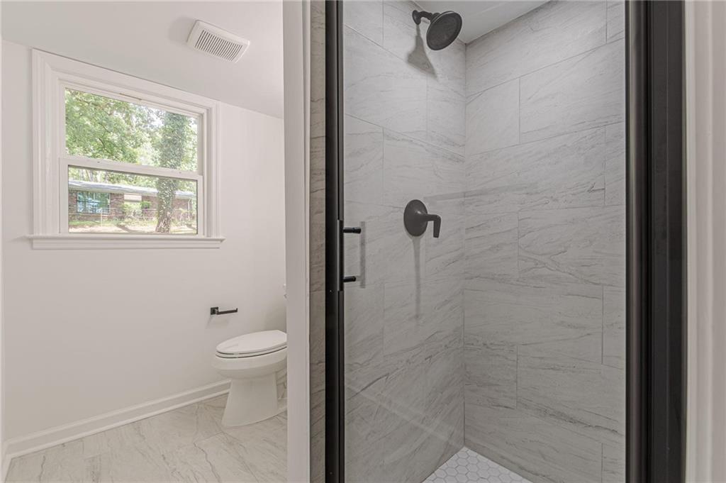 2352 Glendale Drive Decatur, GA 30032 - Photo 35 of 39 a bathroom with a granite countertop toilet a sink a shower and a window