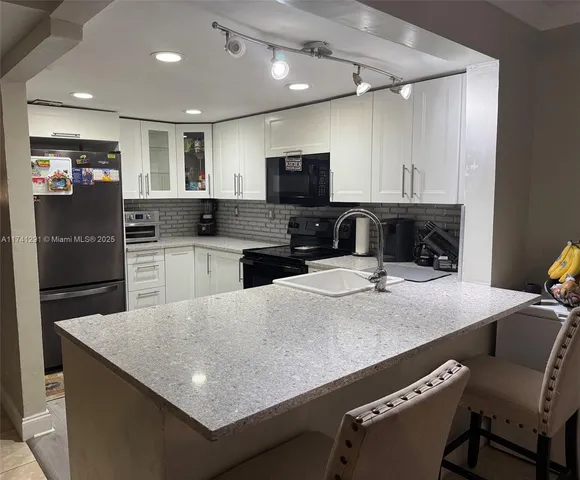 a kitchen with kitchen island white cabinets and stainless steel appliances