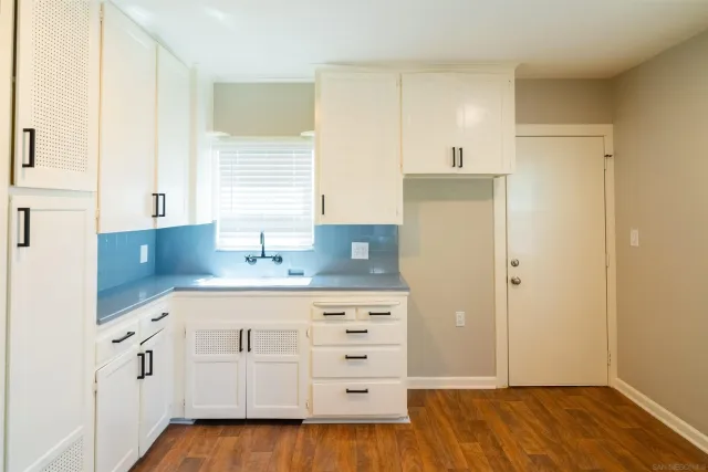 a kitchen with white cabinets and sink