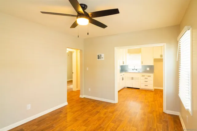 a view of empty room with wooden floor and fan