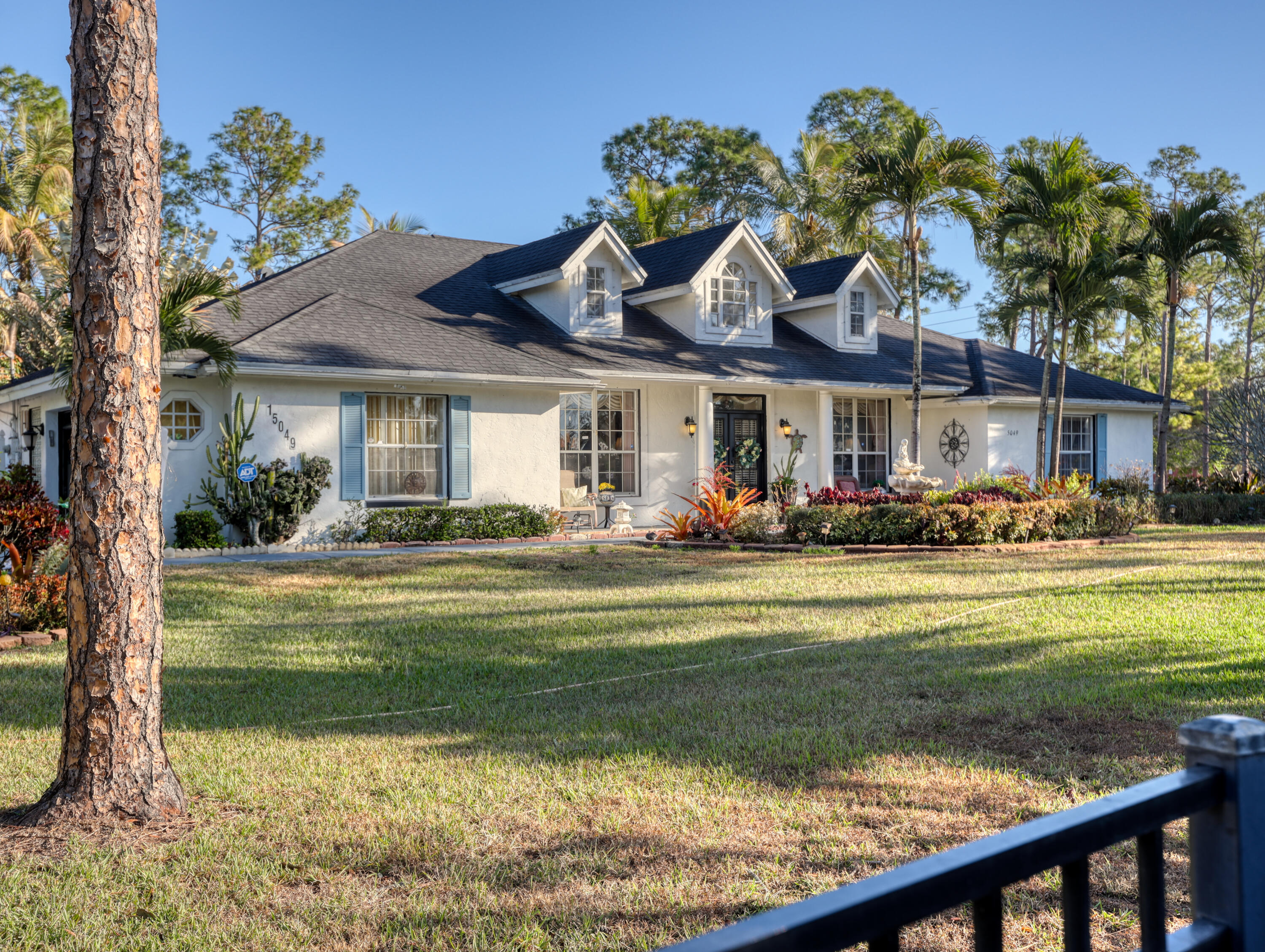 15049 85th Road North The Acreage, FL 33470 - Photo 8 of 60 a front view of a house with a garden and swimming pool