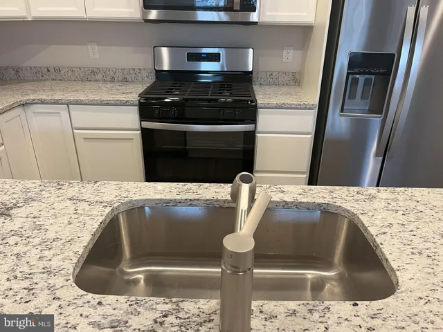 a kitchen with granite countertop a sink and stainless steel appliances