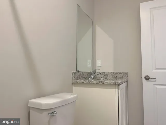 a bathroom with a granite countertop sink and a toilet