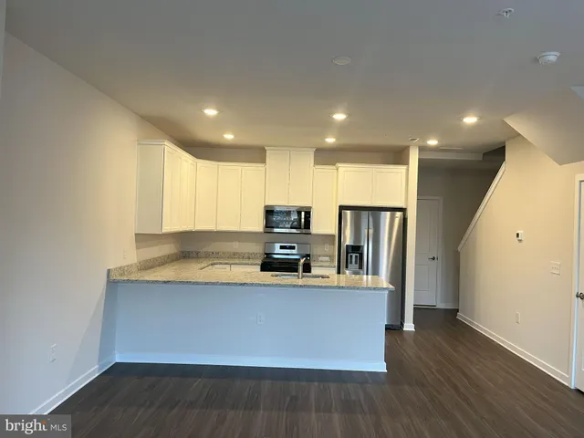 a large kitchen with stainless steel appliances a large counter top a stove and a refrigerator