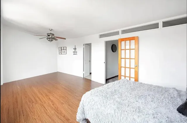 a view of a bedroom with wooden floor and a ceiling fan