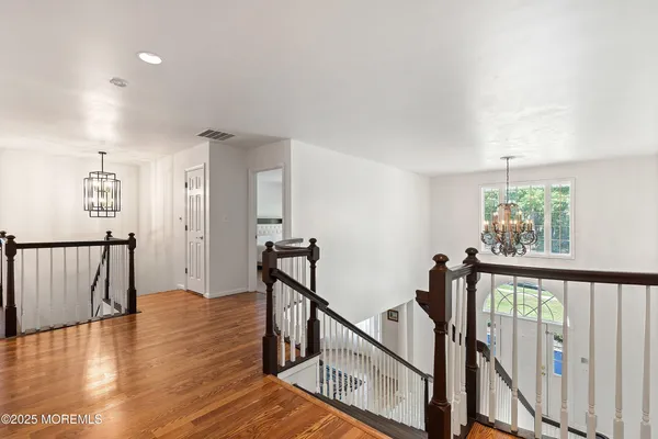 a view of a hallway with wooden floor and stairs