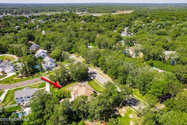 an aerial view of a house with swimming pool and large trees