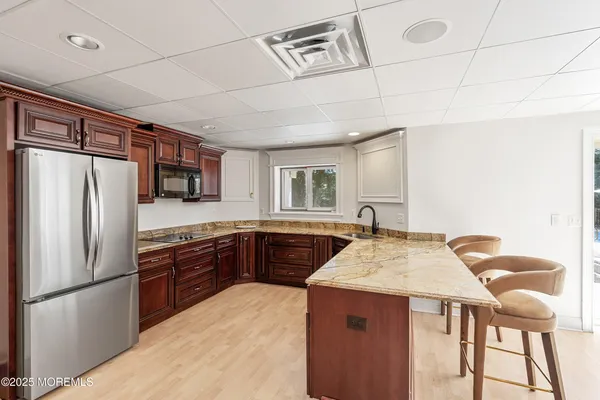 a kitchen with stainless steel appliances granite countertop a refrigerator a sink dishwasher a stove with chairs and wooden floor