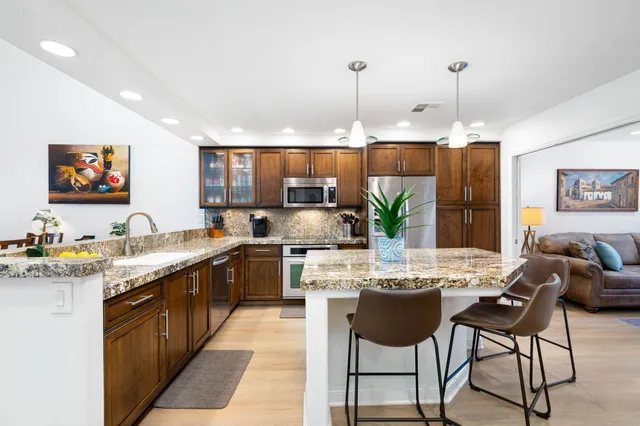 a kitchen with kitchen island granite countertop wooden cabinets and white appliances