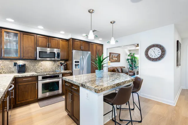 a kitchen with stainless steel appliances granite countertop a kitchen island hardwood floor sink stove and microwave