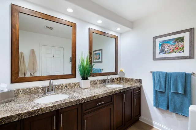 a bathroom with a granite countertop double vanity sink and a mirror
