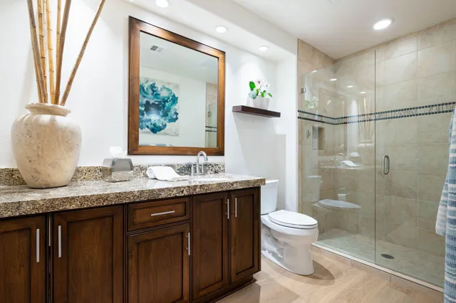 a bathroom with a granite countertop sink toilet and shower