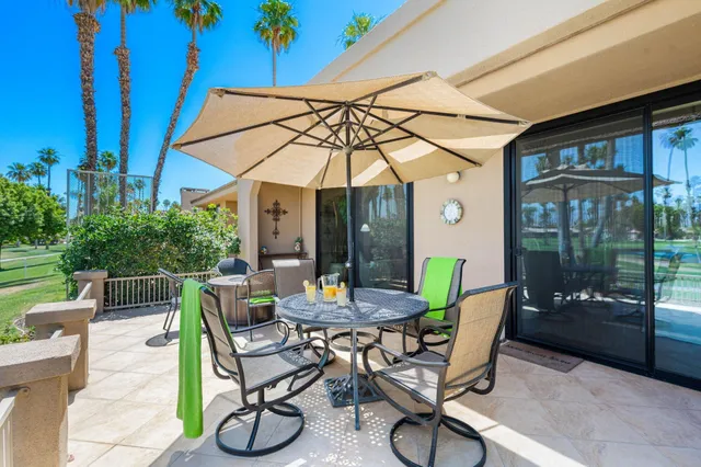 a view of a patio with table and chairs under an umbrella