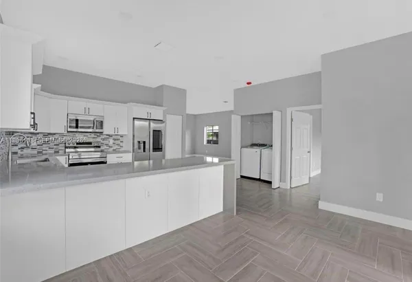a large white kitchen with stainless steel appliances and cabinets