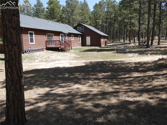 9185 Morgan Road Colorado Springs, CO 80908 - Photo 7 of 23 Back of house. Patio set in treed area.