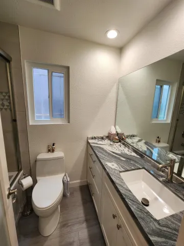 a bathroom with a granite countertop sink a toilet and a mirror