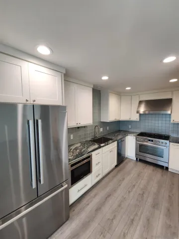a kitchen with stainless steel appliances granite countertop a refrigerator a stove and a sink