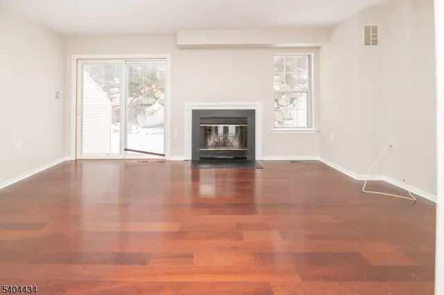 a view of an empty room with window and wooden floor