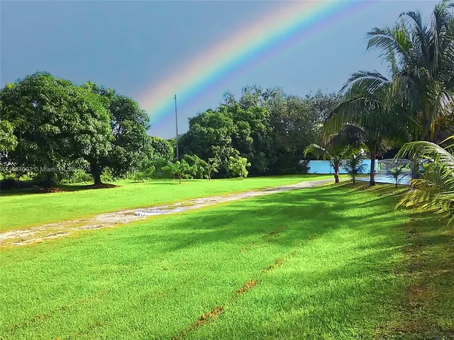 a view of swimming pool with lawn chairs under an umbrella