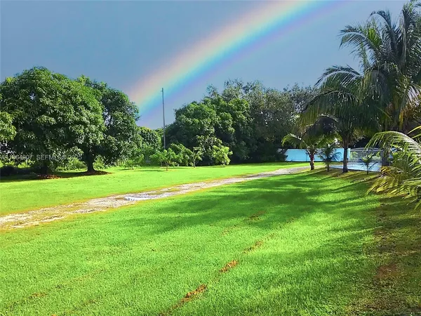 a view of swimming pool with lawn chairs under an umbrella