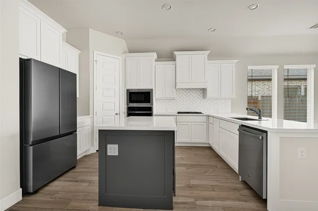a kitchen with stainless steel appliances a refrigerator and a stove top oven
