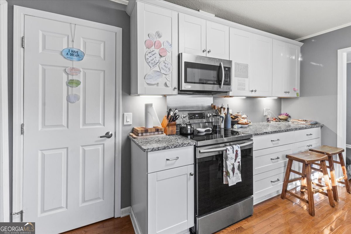 252 Langley Drive LaFayette, GA 30728 - Photo 20 of 29 a kitchen with stainless steel appliances granite countertop white cabinets and stove top oven