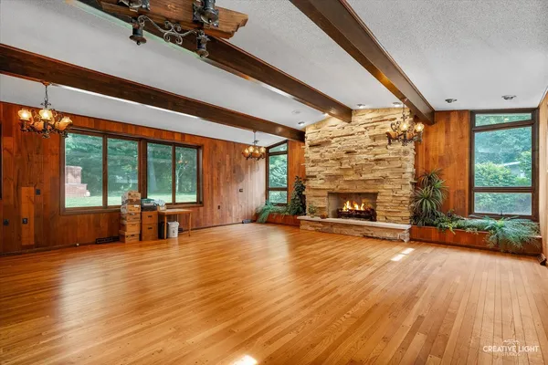 a view of an empty room with wooden floor and a fireplace