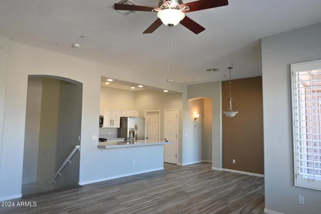 a view of a hallway with wooden floor and a kitchen
