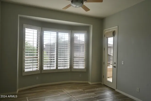 a view of an empty room with a window and wooden floor