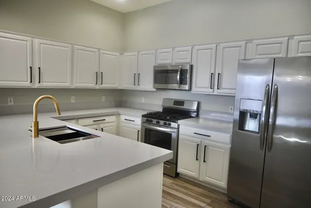 a kitchen with stainless steel appliances granite countertop a sink a stove and refrigerator