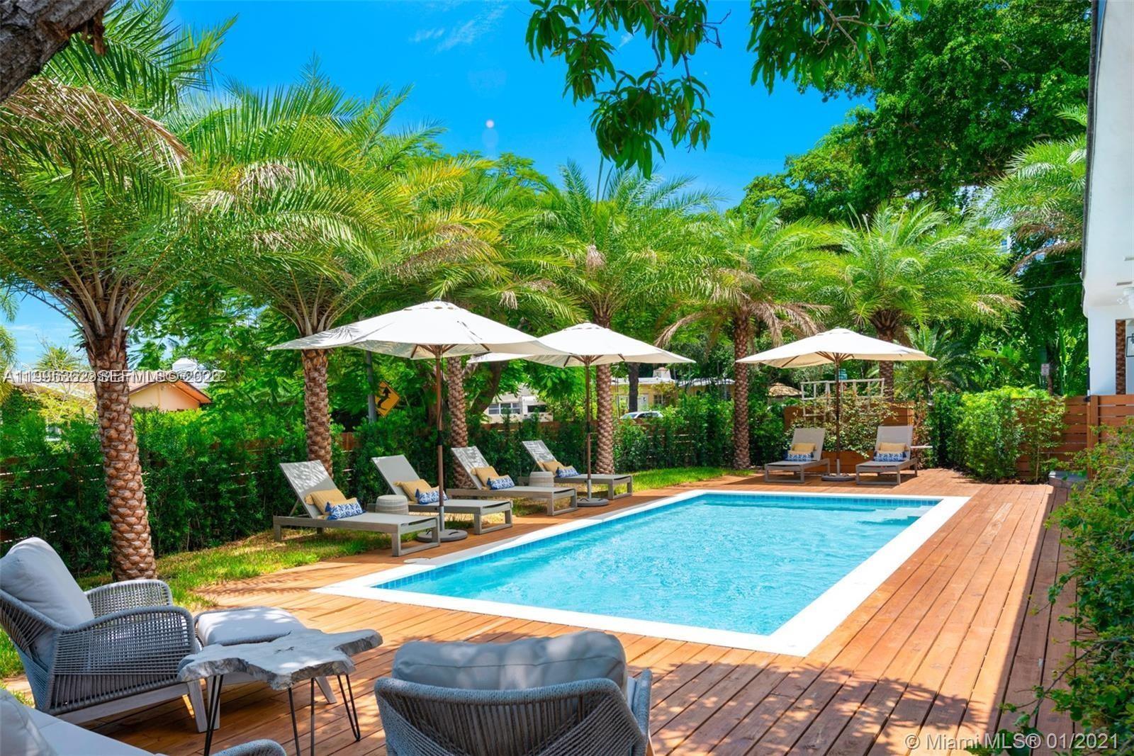 2575 Pine Tree Drive Miami Beach, FL 33140 - Photo 22 of 32 a view of pool with lawn chairs under an umbrella