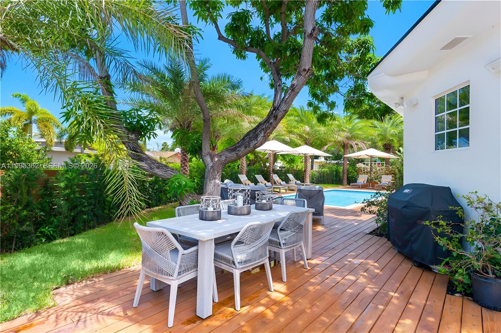 2575 Pine Tree Drive Miami Beach, FL 33140 - Photo 26 of 32 a view of a backyard with table and chairs potted plants and large tree