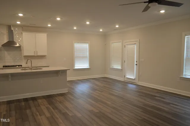 an open kitchen with kitchen island a sink wooden floor and a stove top oven