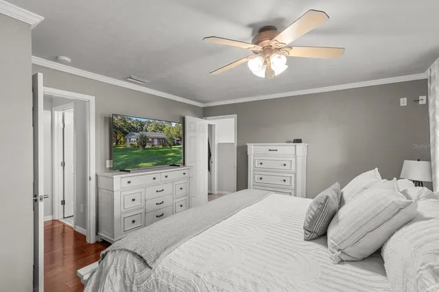 a bedroom with a bed and a flat tv screen on dresser