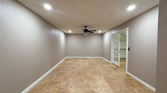 an empty room with a ceiling fan and carpet