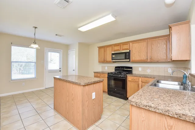 a kitchen with stainless steel appliances granite countertop a stove top oven a sink a counter top space and cabinets