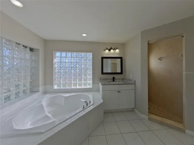 a spacious bathroom with sink shower and mirror