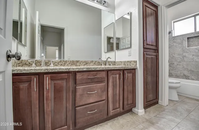 a bathroom with a granite countertop sink and a toilet
