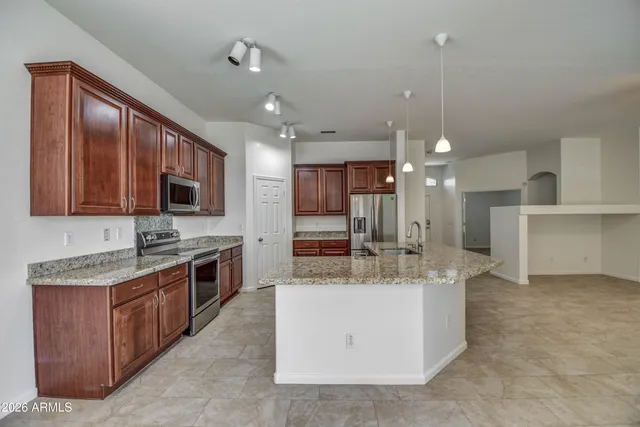 a large kitchen with stainless steel appliances kitchen island granite countertop a sink counter space and cabinets