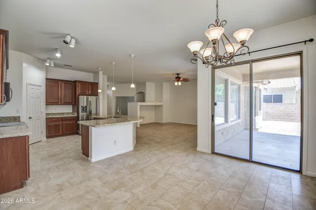a view of a kitchen with granite countertop a large counter top space stainless steel appliances and a chandelier