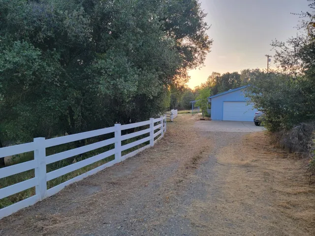 a view of backyard with wooden fence and large trees