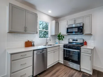 a kitchen with a refrigerator a stove top oven a sink and dishwasher with wooden floor