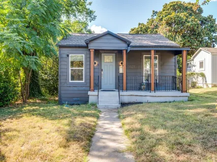 a view of a brick house with large windows and a small yard