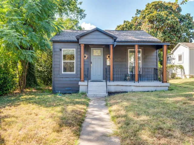 a view of a brick house with large windows and a small yard