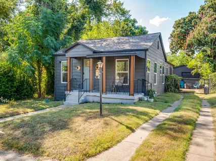 a view of a house with a yard potted plants and large tree
