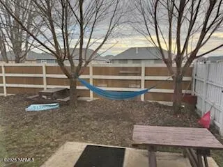 a view of a white house next to a yard with large trees