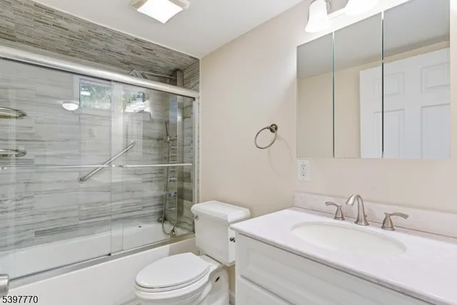 a bathroom with a granite countertop sink toilet a mirror and shower