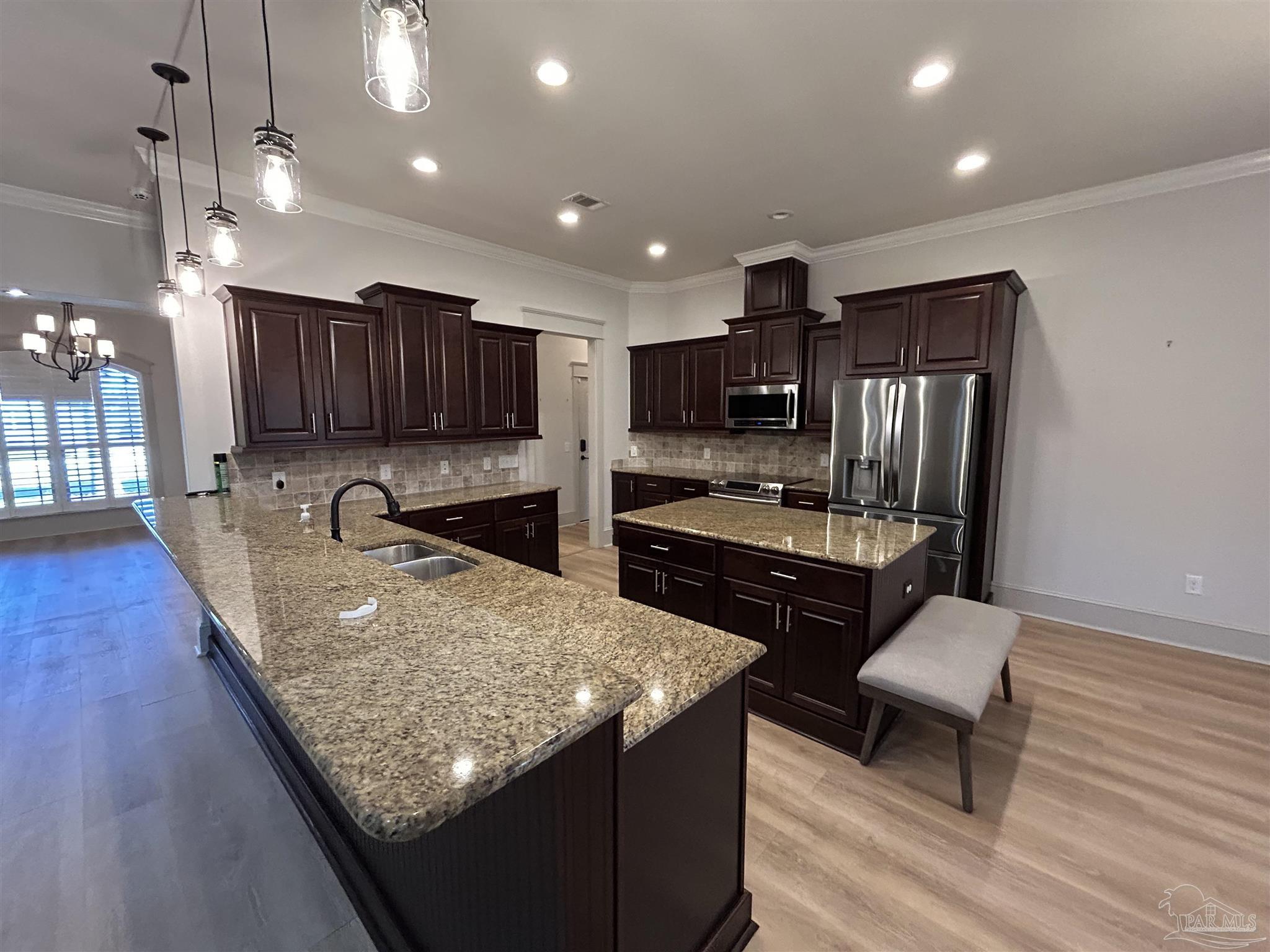 4081 Manchester Court Pace, FL 32571 - Photo 15 of 34 a kitchen with stainless steel appliances granite countertop a table chairs sink refrigerator and microwave